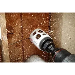 2" Hole Dozer with Carbide Teeth drilling through a wooden surface, creating sawdust and wood chips with a cordless power drill.