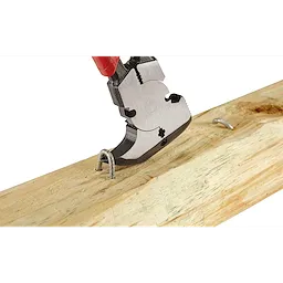 Comfort Grip Fencing Pliers are being used to remove a metal staple from a wooden board. The pliers have a red handle and a multi-functional head designed for gripping and cutting various wire types.