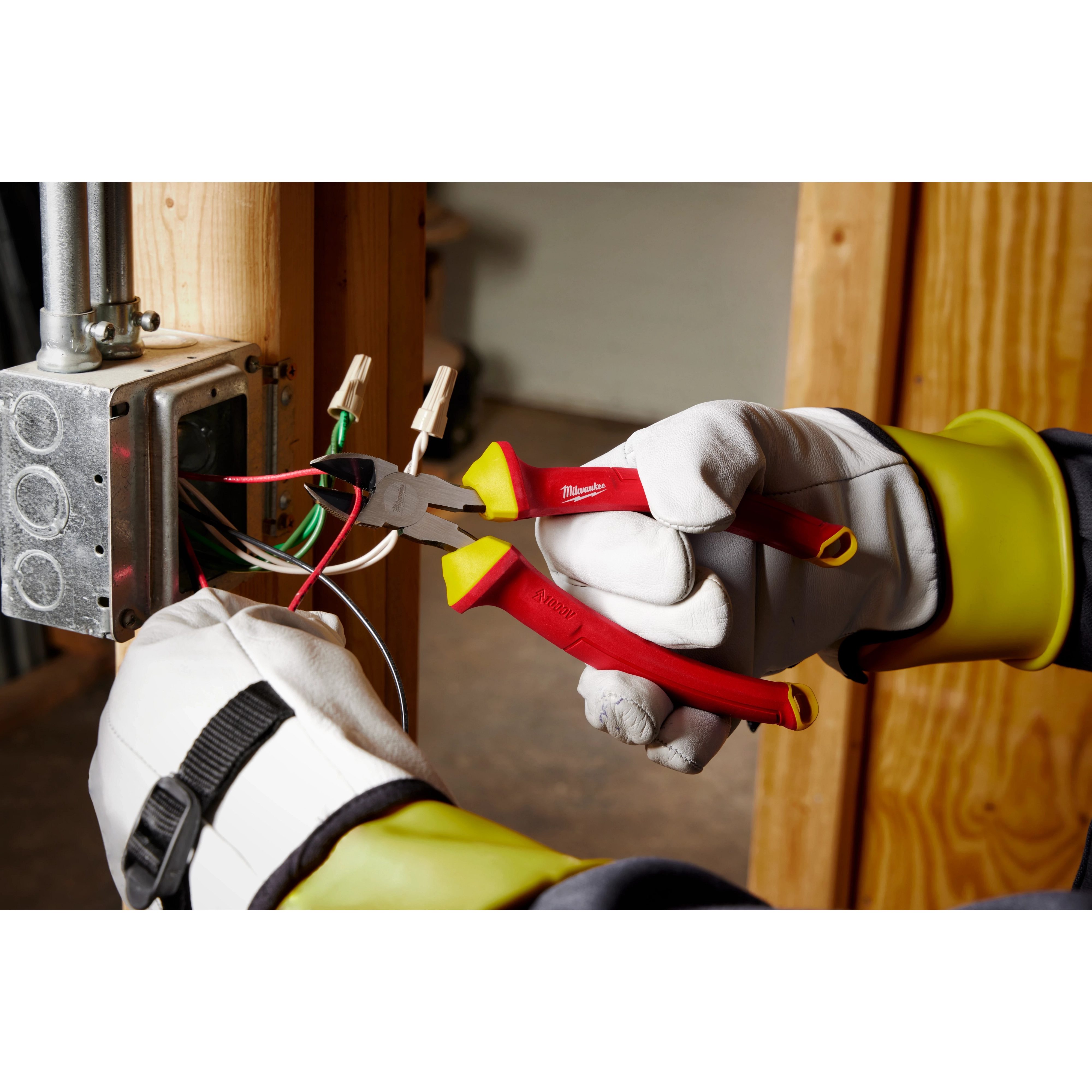 Technician using 1000V Insulated 8" Diagonal Cutting Pliers to cut wires in an electrical box. The worker wears gloves for safety.