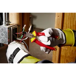 Technician using 1000V Insulated 8" Diagonal Cutting Pliers to cut wires in an electrical box. The worker wears gloves for safety.