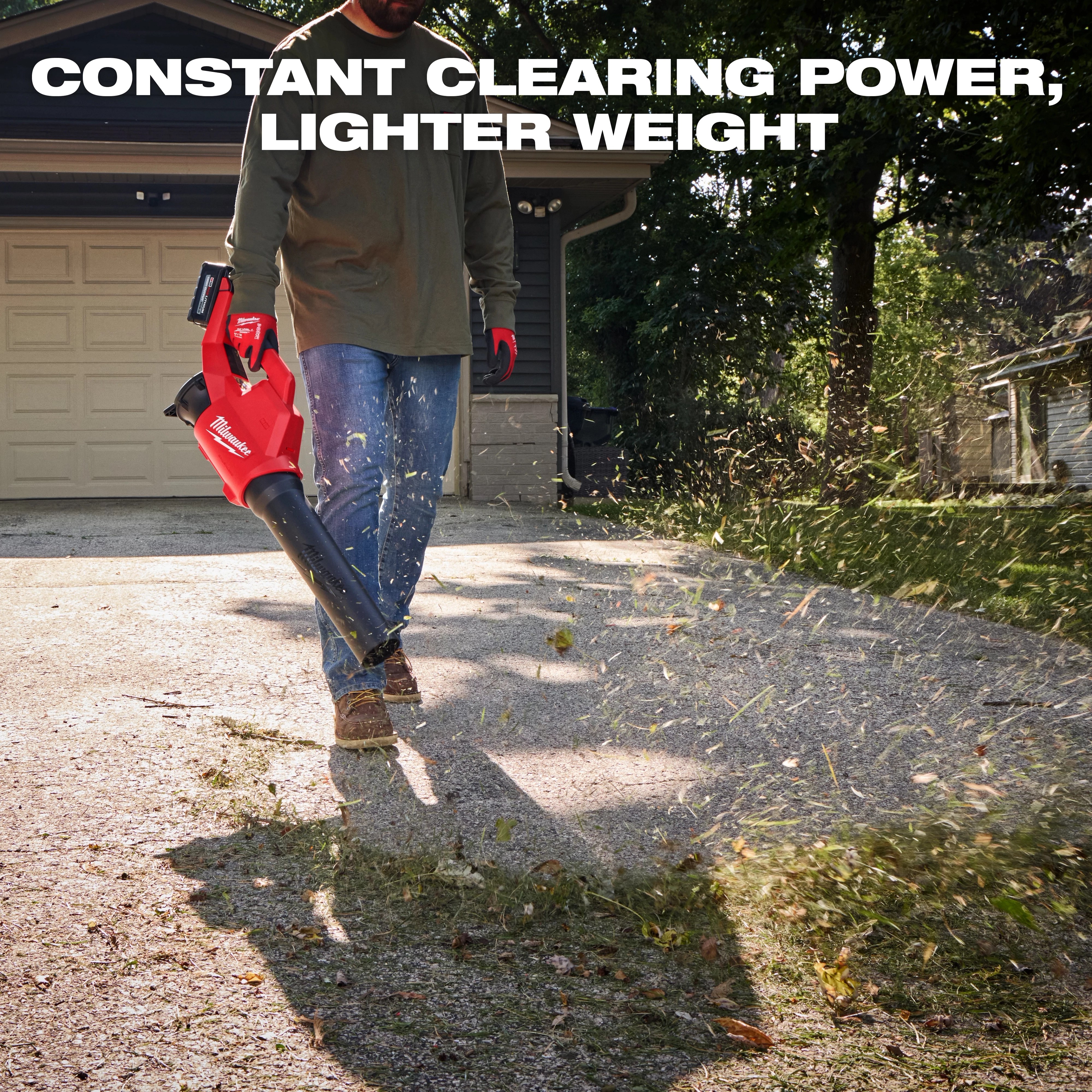 A person uses the Milwaukee M18 Brushless Blower to clear debris on a driveway in front of a garage. The text reads "Constant Clearing Power, Lighter Weight" above it.