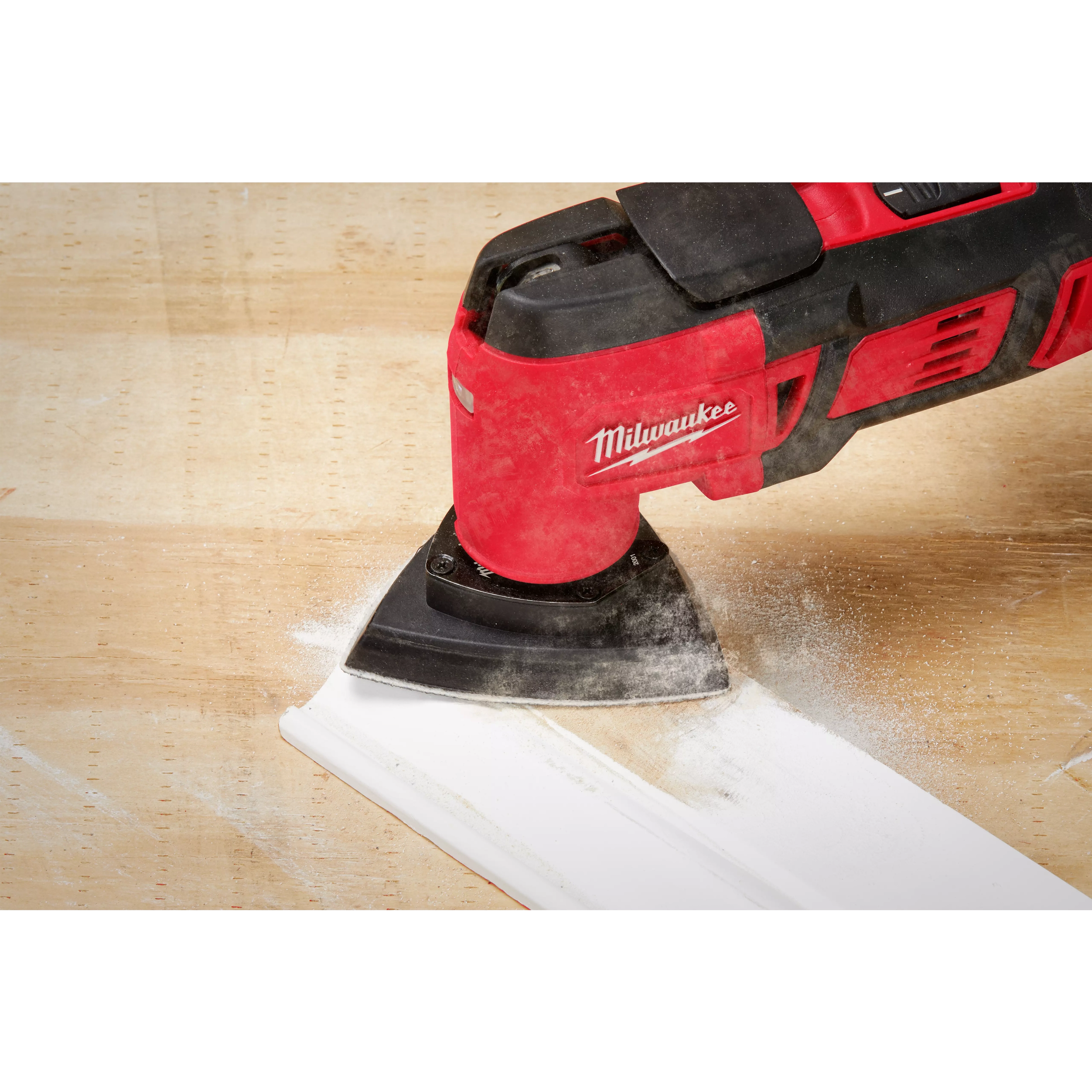 Milwaukee OMT Blades, 3-1/2" Triangle Sanding Pad in use on a wooden surface, creating white dust while smoothing the edge.
