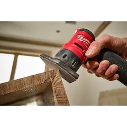 A hand using an M12 FUEL Orbital Detail Sander equipped with 180 Grit Mesh Sanding Sheets to smooth a wooden surface.