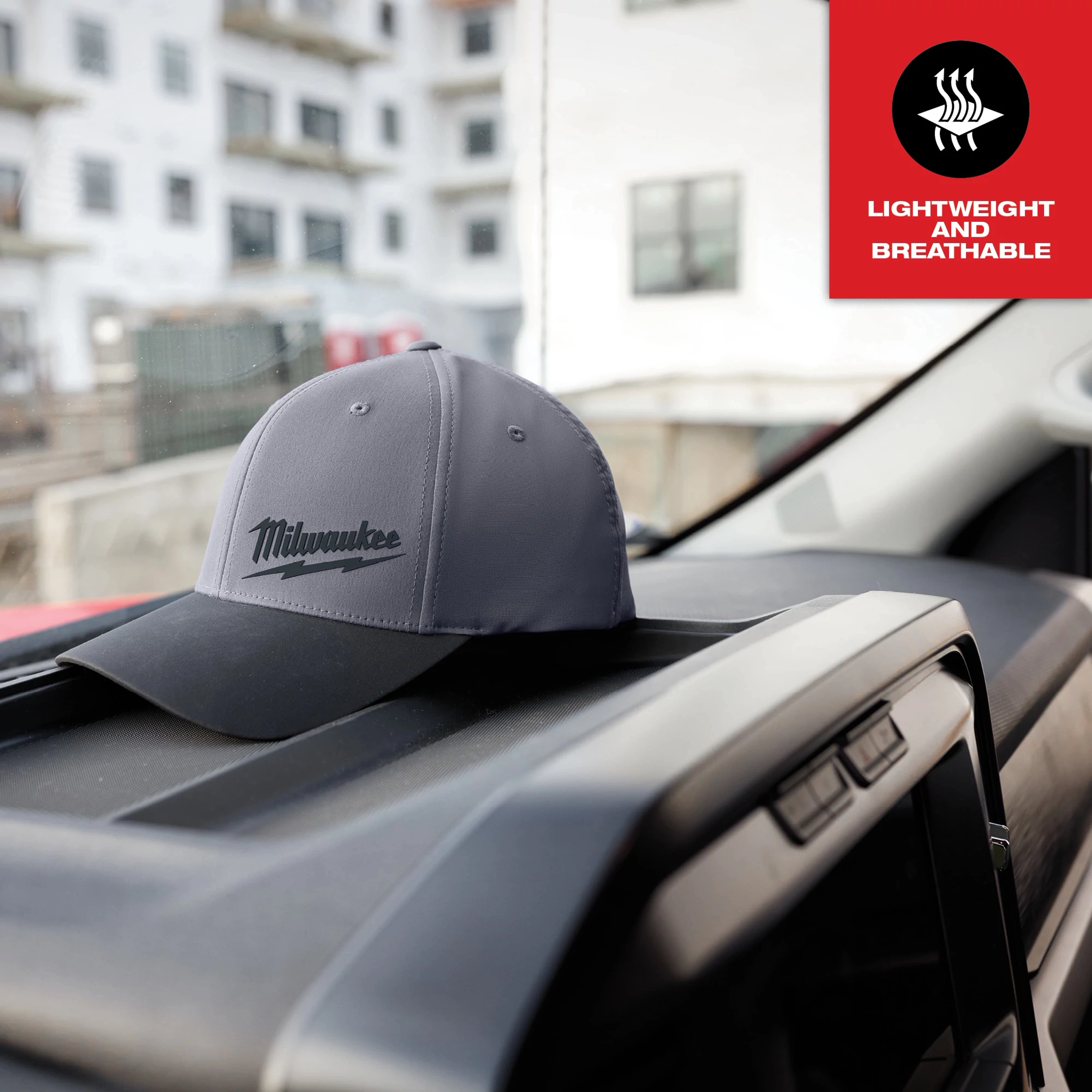 WORKSKIN Performance Fitted Hat in dark gray with black brim on car dashboard. Text overlay reads “Lightweight and Breathable.”
