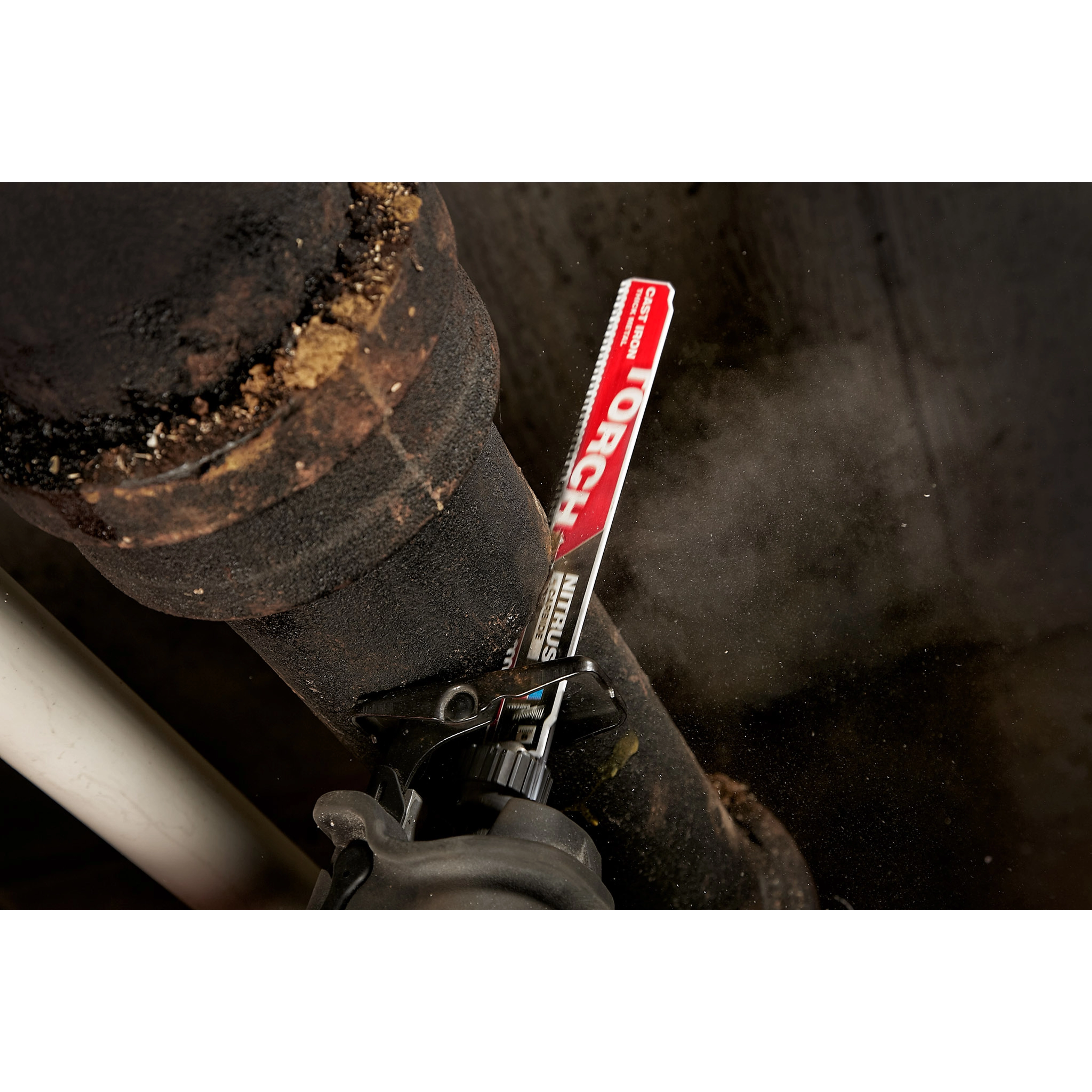 Milwaukee 9” CAST IRON, TORCH w. Nitrus Carbide Sawzall Blade cutting through a rusted, black iron pipe with sparks and dust.