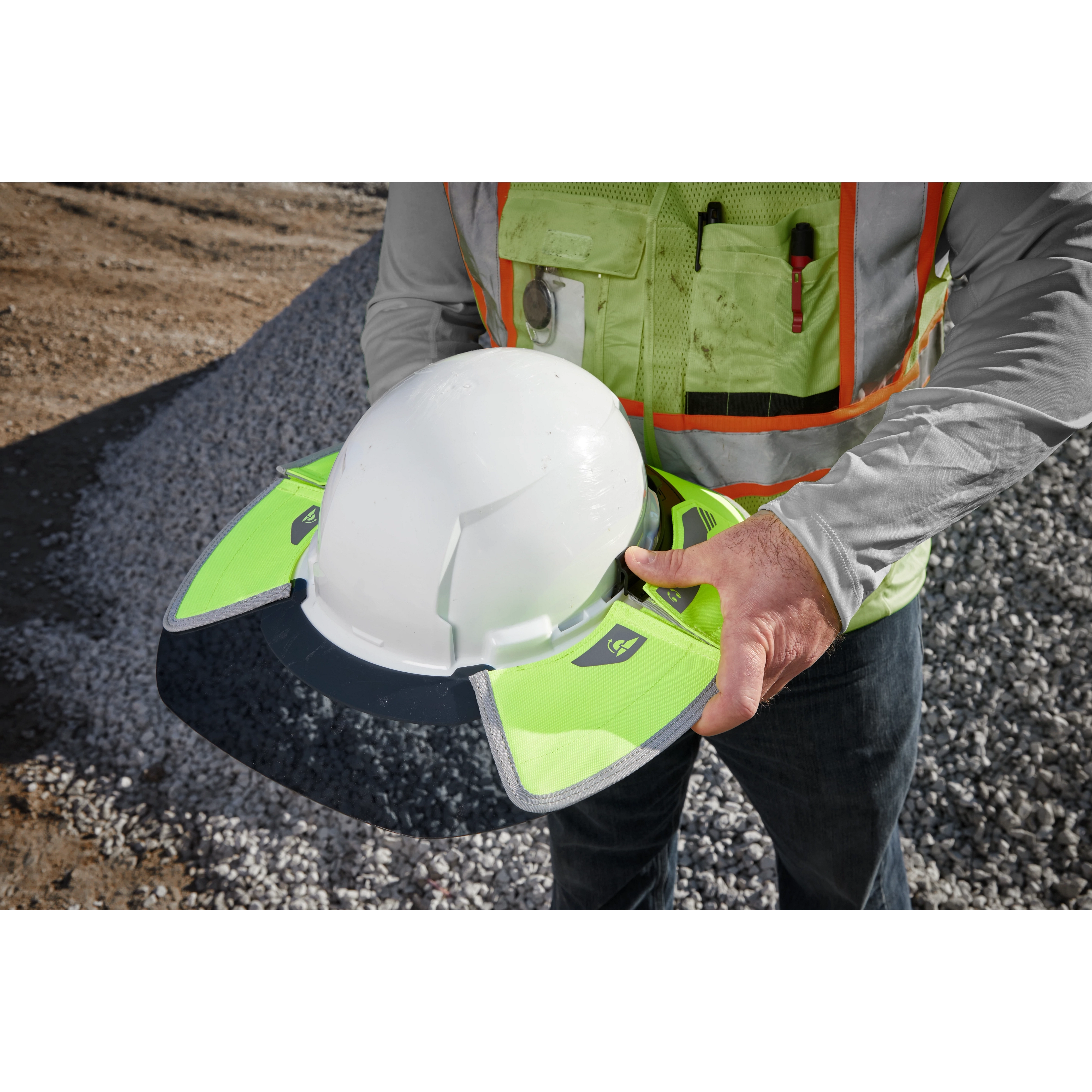 A person is holding a hard hat fitted with a BOLT Sun Visor. The sun visor is neon green with reflective elements and designed to attach to a standard hard hat for added shade and visibility.