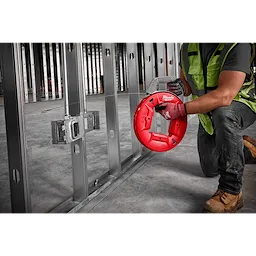 A construction worker using a 240' 1/8" Stainless Steel Fish Tape to guide wiring through metal studs in an unfinished wall.