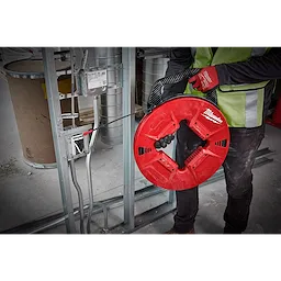 Person using 200% Polyester Fish Tape with Non-conductive Tip to pull wires through metal framing at a construction site.