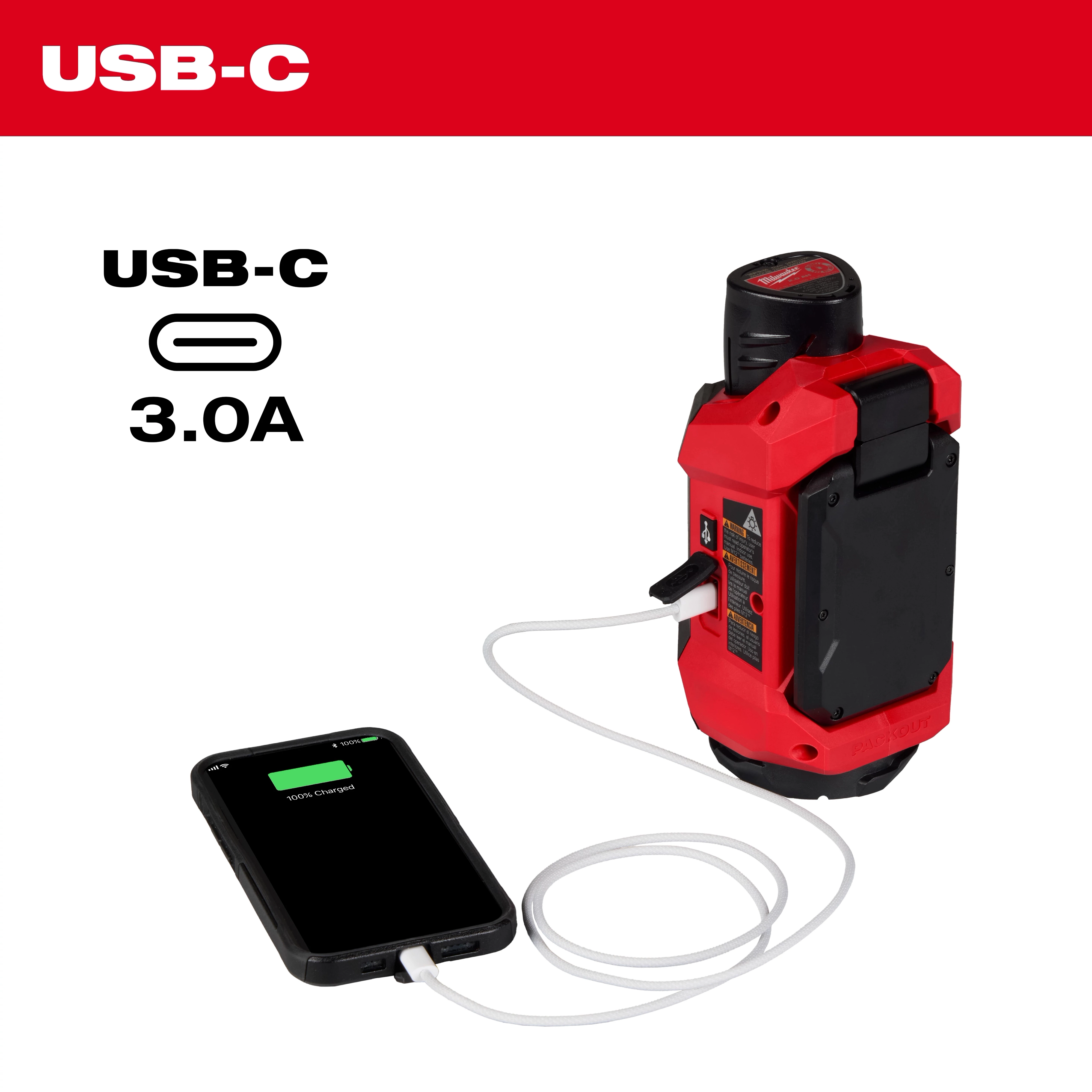 The M12™ ROVER™ Multi-Directional Flood Light w/ PACKOUT™ Compatibility is shown charging a smartphone via a USB-C port. Text highlights "USB-C 3.0A" at the top left. The light is red and black, with charging cables connected.