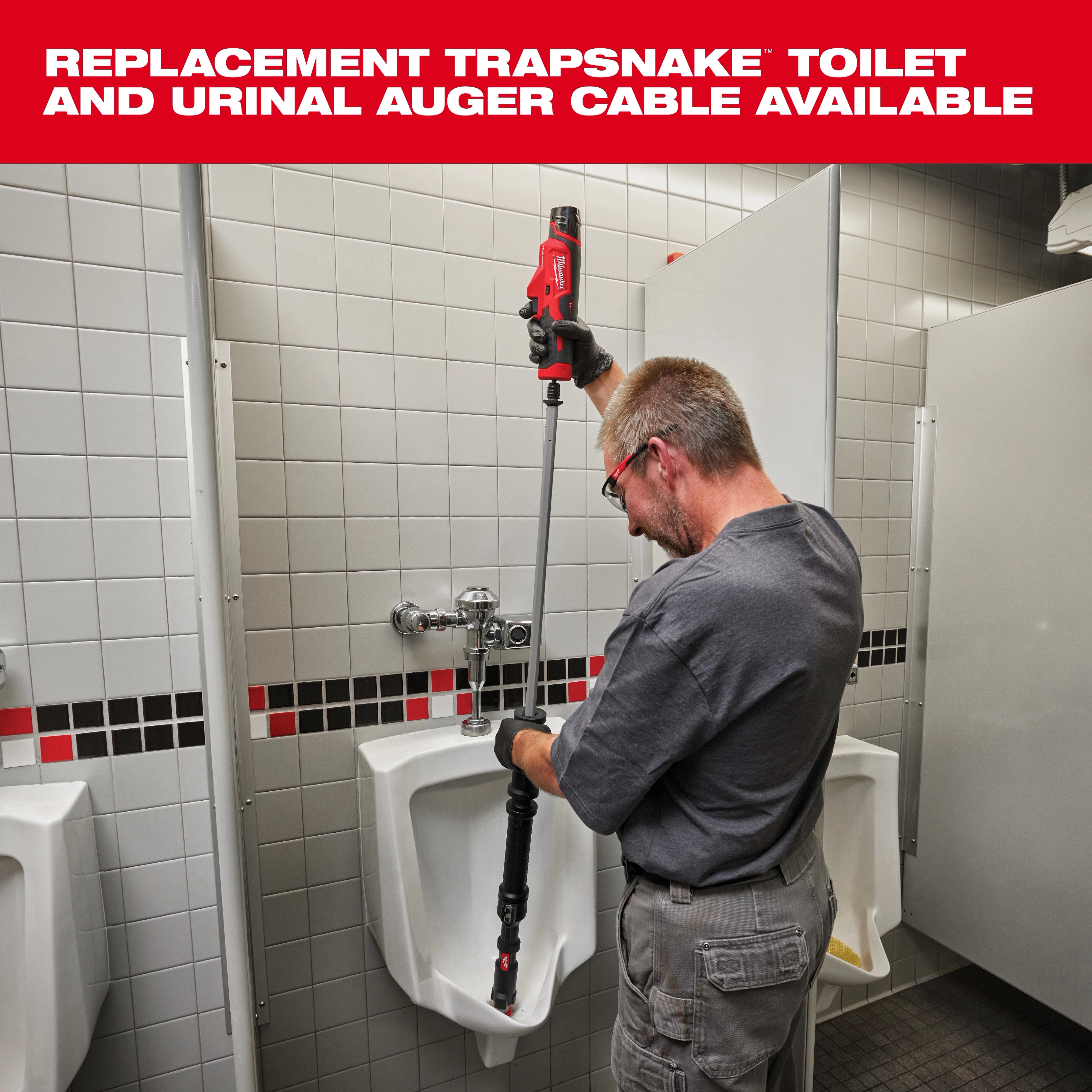 A person is using the Trapsnake toilet and urinal auger to clean a commercial urinal in a public restroom. The auger is a long tool with a red handle designed for unclogging and maintaining plumbing. Text above indicates availability of replacement cables for the Trapsnake auger.