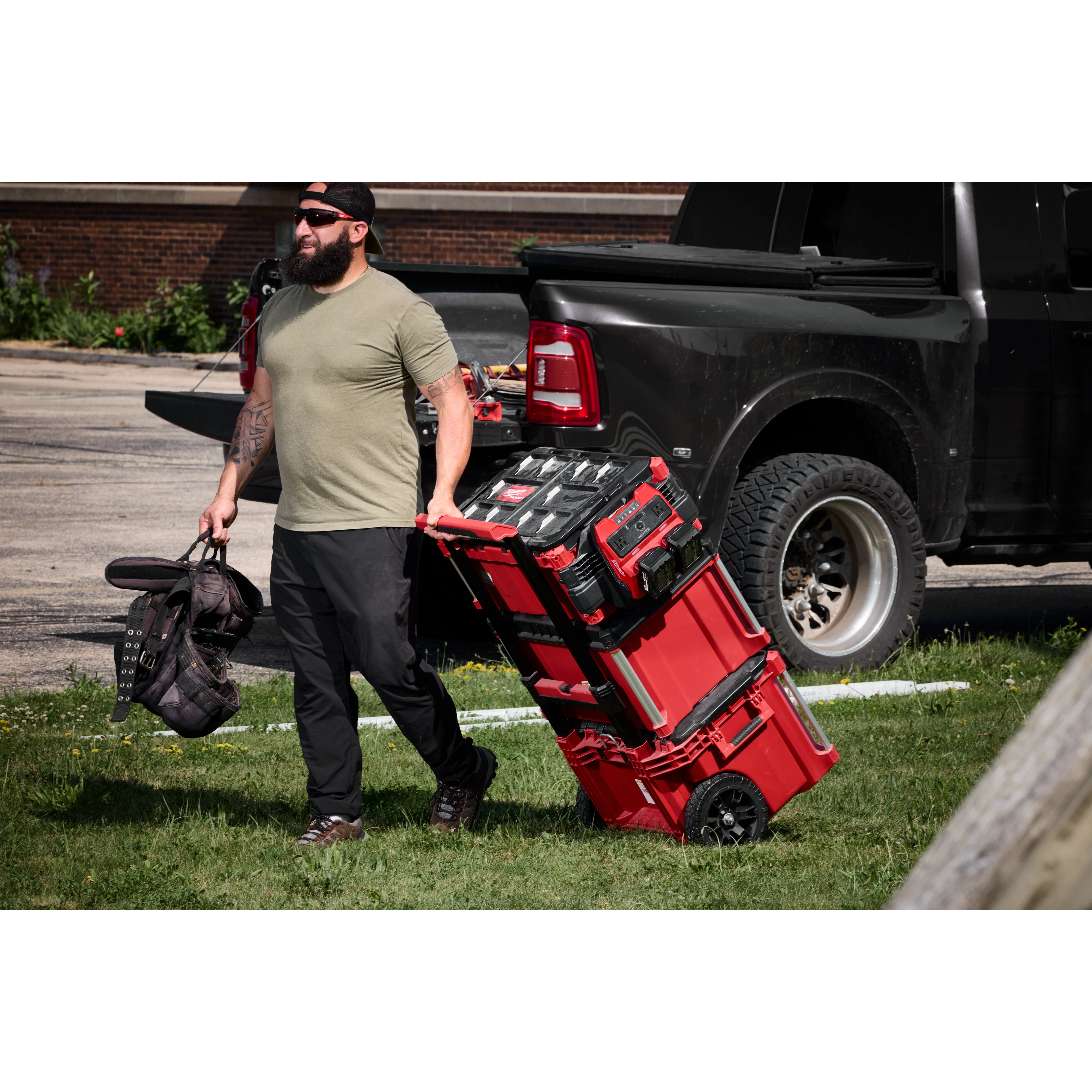 Worker pulling stacked tool boxes featuring the M18 TOP-OFF 350W Power Supply & Charger w/ PACKOUT Compatibility.
