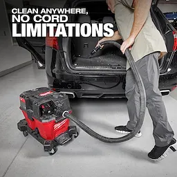 A person uses the M18 FUEL™ NEXUS™ 6 Gallon Wet/Dry Vacuum to clean the trunk of a black car in a garage, highlighting the vacuum’s portability with no cord limitations.