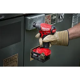 A gloved hand using the Penta%20Socket tool on a metal surface, marked with high voltage caution stickers.