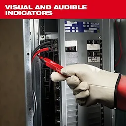 A gloved hand uses a Milwaukee voltage tester on an electrical panel. The device features visual and audible indicators, as highlighted in the text above the image.