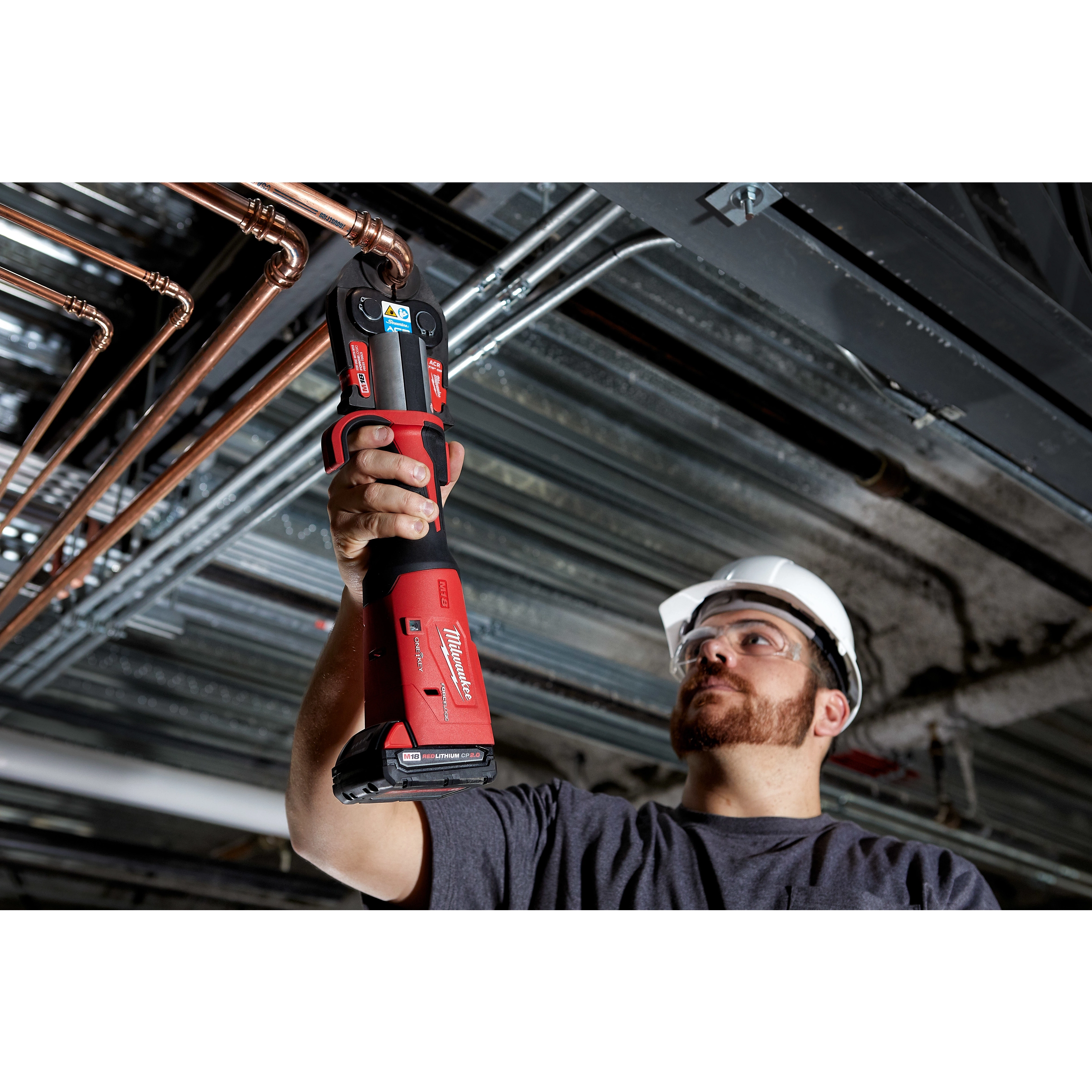 A construction worker uses the M18 FORCE LOGIC Press Tool Kit with One-Key and 1/4"-7/8" Streamline ACR Jaws on copper pipes.