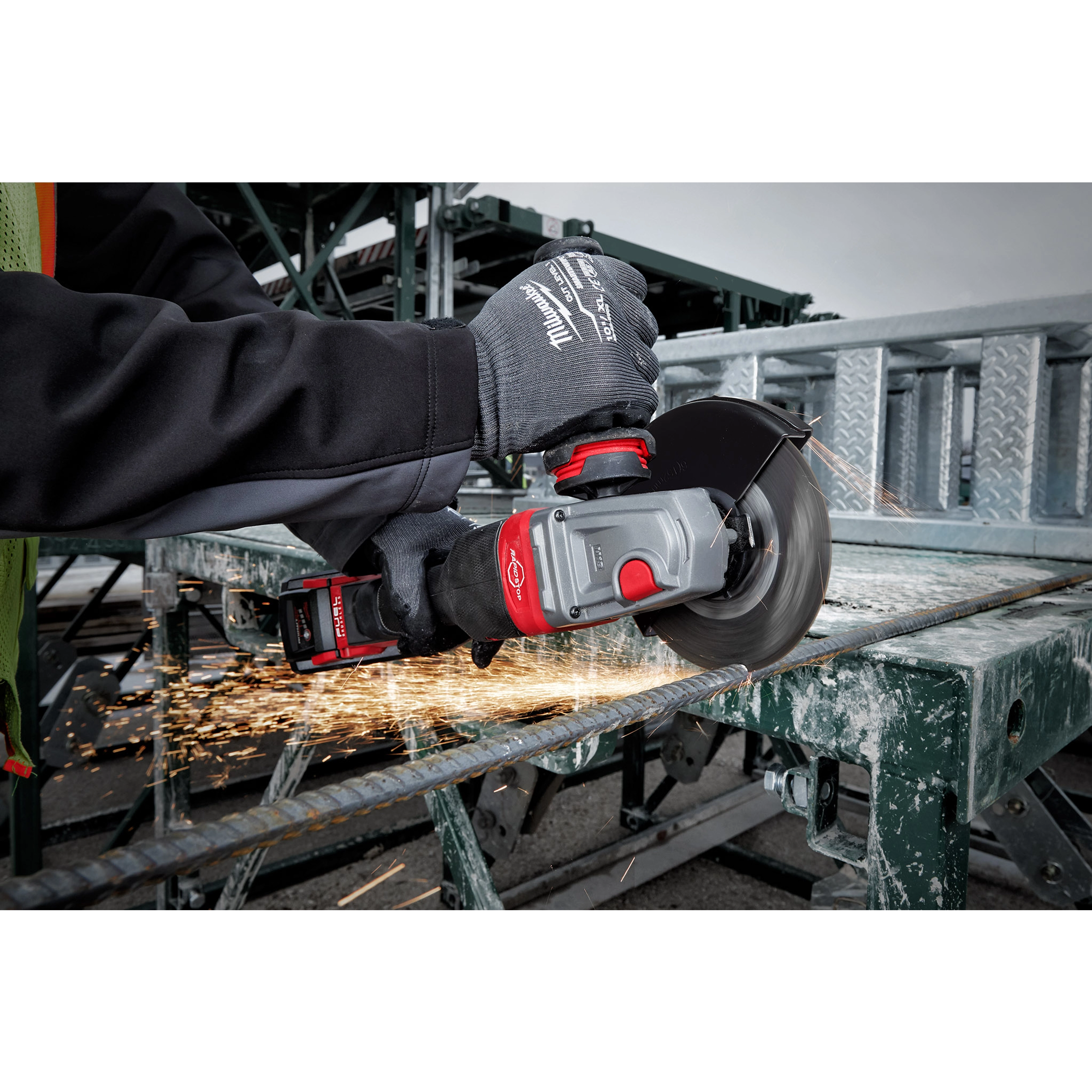 Person using the M18 FUEL 4-1/2" - 6" Braking Grinder Paddle Switch, No-Lock to cut a metal rod, wearing safety gloves.