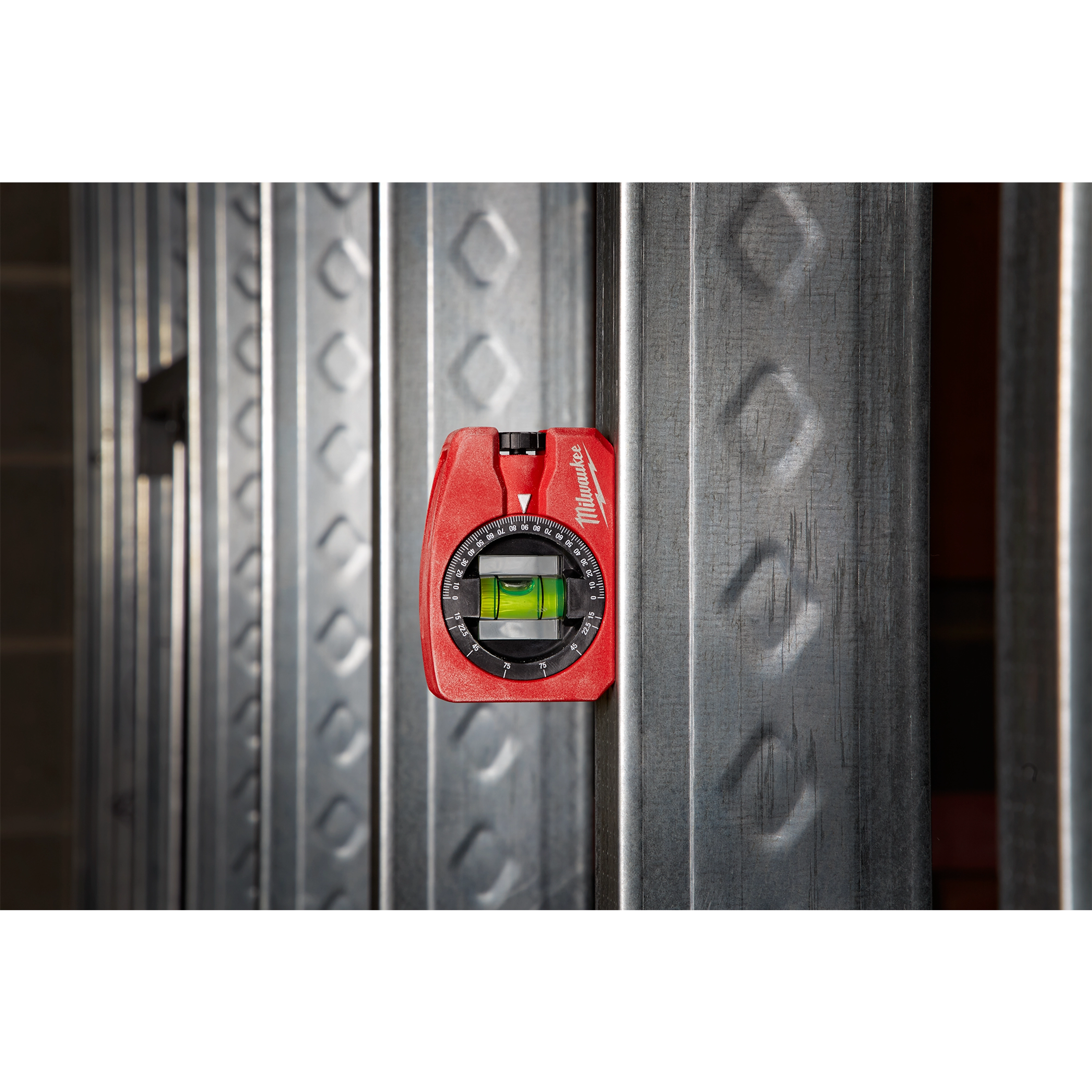 Milwaukee Pocket Level magnetically attached to a steel beam, featuring a red body and a circular vial for precise leveling.