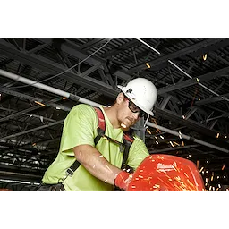 Worker in a green shirt using a power tool in a workshop with sparks flying and wearing Performance Safety Glasses - Gray Fog-Free Lenses.