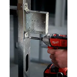 A person using a power drill with a Magnetic Bit Holder to install screws into a metal electrical box mounted on a frame.