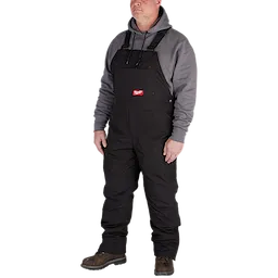 A person wears FREEFLEX Insulated Bib Overalls, featuring adjustable black straps, multiple pockets, and a gray hoodie underneath.